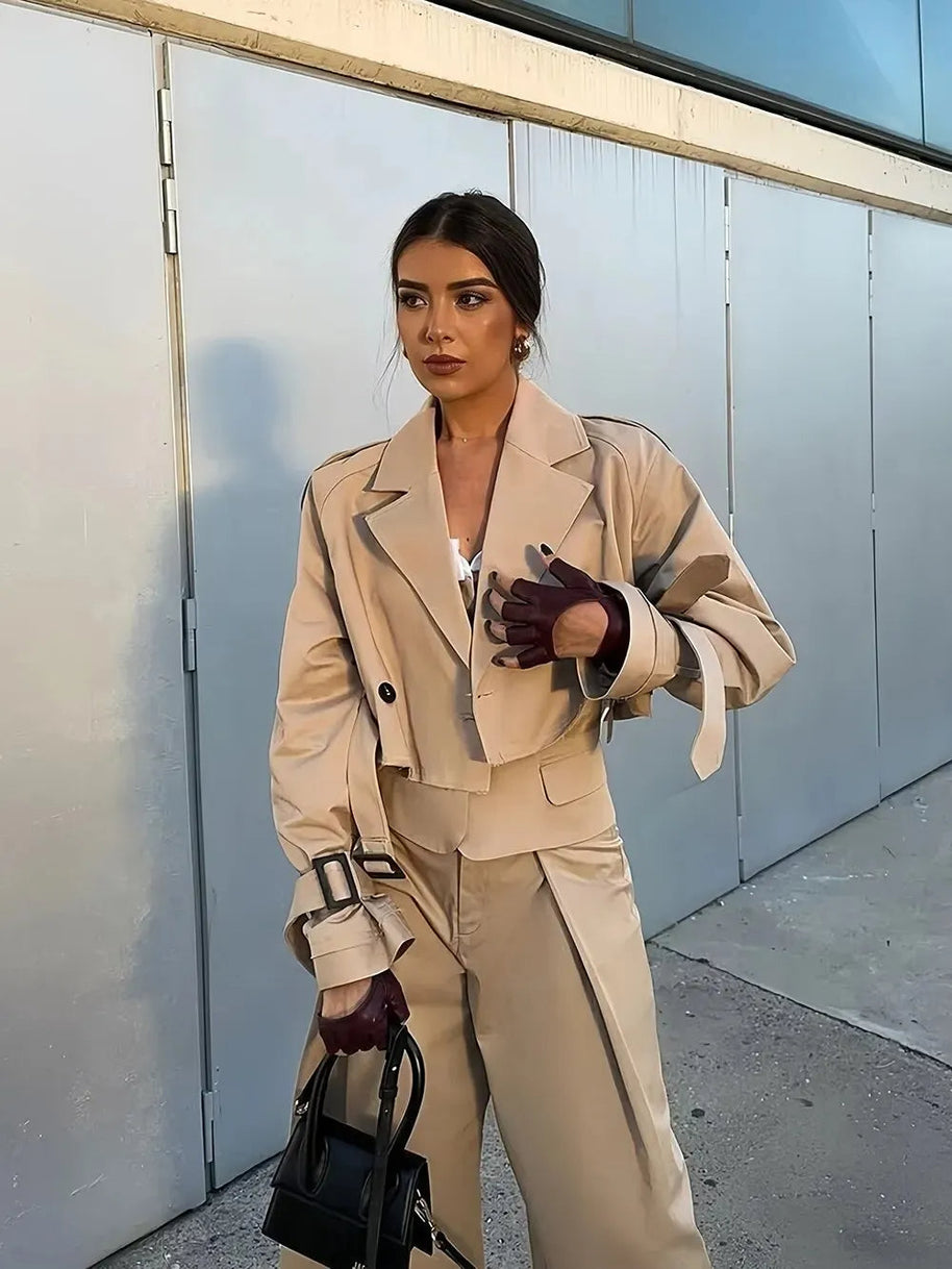 Ein Model in einer kurzen Jacke und Khakihosen, während es eine schwarze Tasche hält