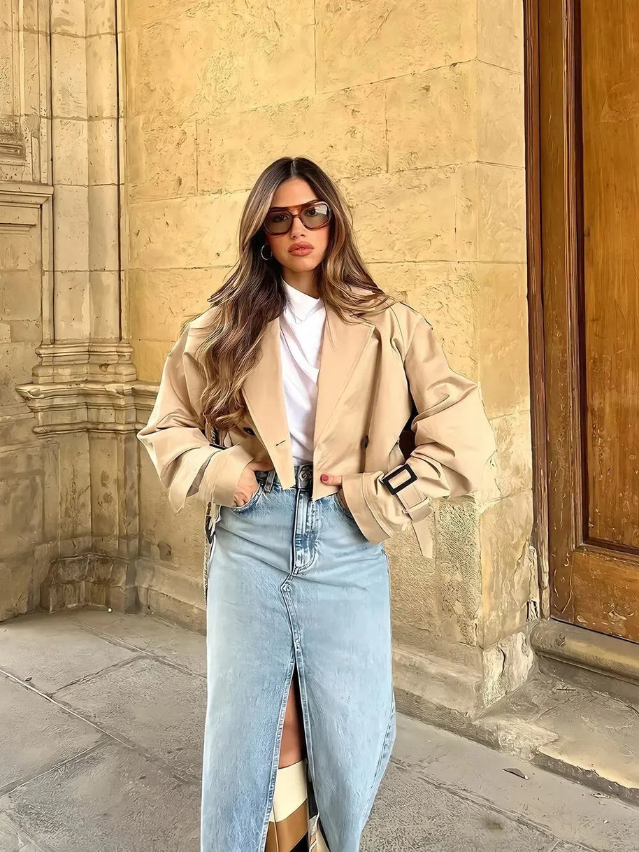 Ein Model trägt eine offene Kurzjacke mit weißem Innenoberteil und langem Jeansrock mit Schlitz