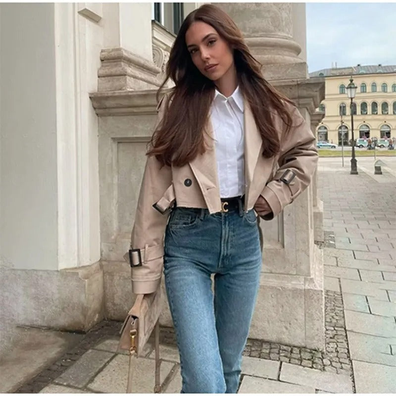Eine Frau trägt eine offene Kurzjacke mit weißem Innenoberteil und Jeanshose