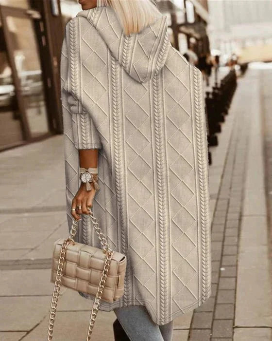 Rückansicht einer Frau, die eine beige Strickjacke mit Kapuze und hellblaue Jeans trägt und eine dazu passende beige gesteppte Handtasche mit Kette hält.