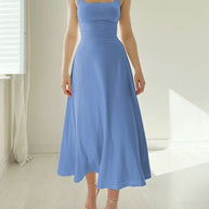 Frau trägt ein blaues ärmelloses Midikleid mit tailliertem Oberteil und weitem Rock.