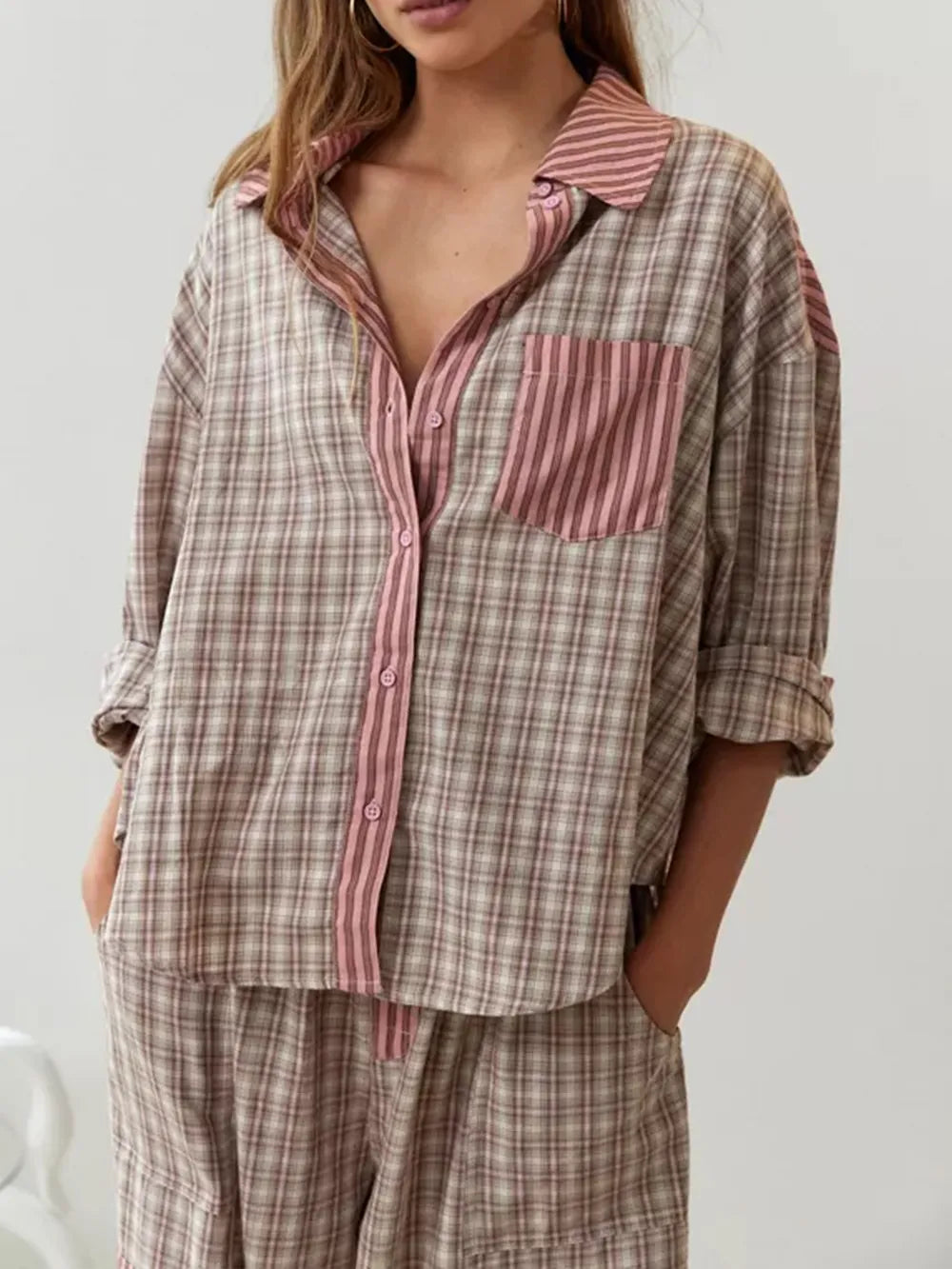 Eine Frau trägt ein 2-teiliges braunes, lässiges Pyjama-Set mit Karomuster
