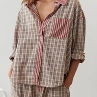 Eine Frau trägt ein 2-teiliges braunes, lässiges Pyjama-Set mit Karomuster