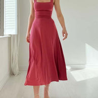 Frau trägt ein rosa ärmelloses Midikleid mit tailliertem Oberteil und weitem Rock.