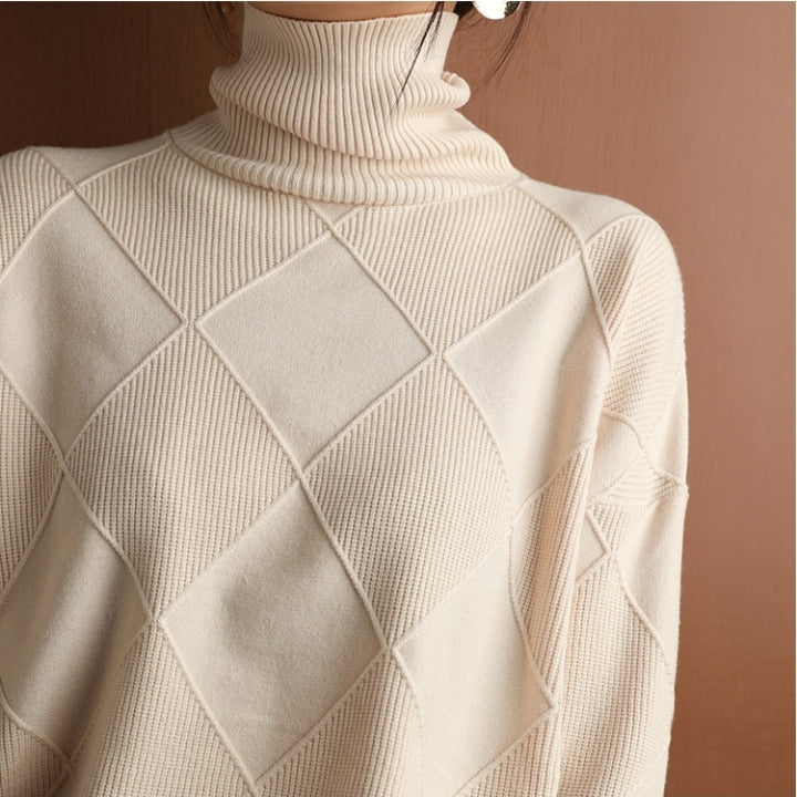 Eine Frau trägt einen beige Rollkragenpullover mit brauner Tasche