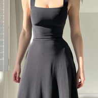 Frau trägt ein schwarzes ärmelloses Midikleid mit tailliertem Oberteil und weitem Rock.