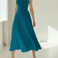 Frau im blaugrünen Kleid mit breiten Trägern