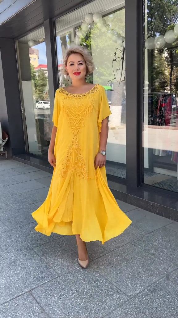 Frau in lockerem, mehrlagigem gelbem Kleid und beigen High Heels