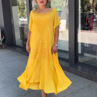 Frau in lockerem, mehrlagigem gelbem Kleid und beigen High Heels