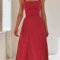 Eine Frau trägt ein ärmelloses Midikleid mit tailliertem Oberteil und weitem Rock.