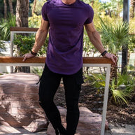 Ein Mann trägt ein lila Essential T-Shirt mit tiefem Schnitt