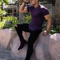 Ein Mann trägt ein lila Essential T-Shirt mit tiefem Schnitt