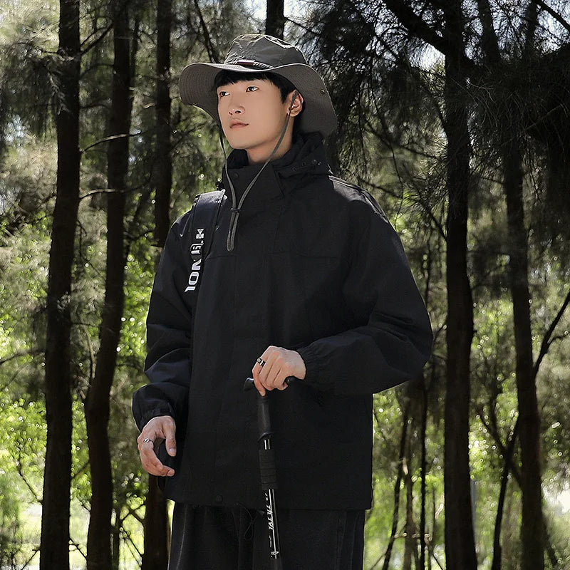 Ein Mann trägt eine wind- und wasserdichte Outdoor-Kapuzenjacke mit langen Ärmeln und farblich abgestimmtem Reißverschluss