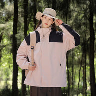 Ein Mann trägt eine rosaa wind- und wasserdichte Outdoor-Kapuzenjacke mit langen Ärmeln und farblich abgestimmtem Reißverschluss