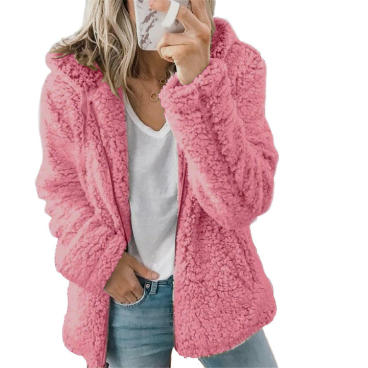 Eine Frau trägt einen rosa Pelzmantel mit Tasche und Reißverschluss, eine Hand auf der Tasche auf weißem Hintergrund