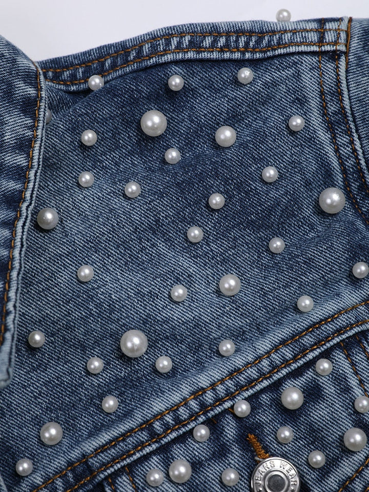 Nahaufnahme, die das Detail einer Jeansjacke mit weißer Perlenverzierung zeigt