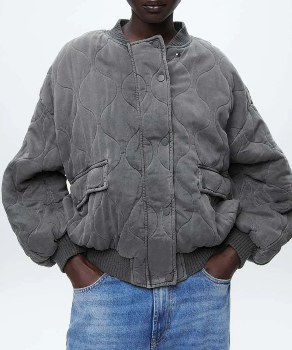 Ein model posiert in einer locker geschnittenen graue bomberjacke