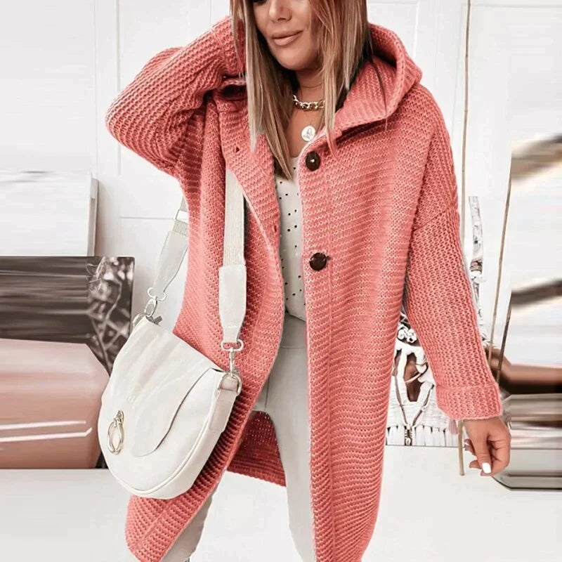 Eine Person trägt eine lange, warme rote Strickjacke mit Kapuze und zwei schwarzen Knöpfen