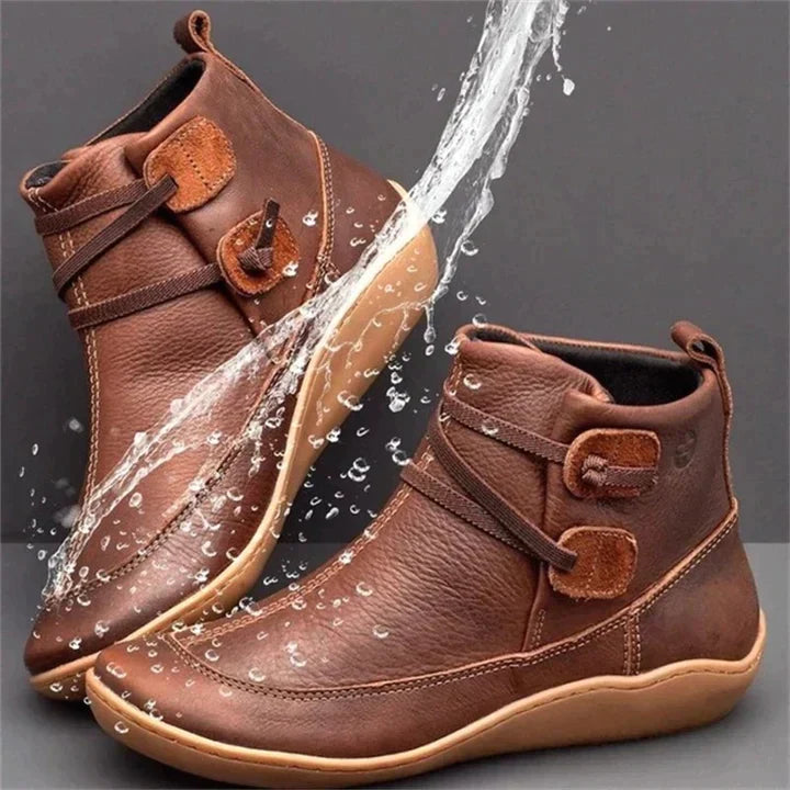 Ein paar braun orthopädische stiefel mit wasserspritzern darum herum
