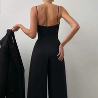 Rückenansicht eines model in einem schwarz sexy riemen-overall, das einen blazer hält