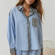 Eine Frau trägt ein 2-teiliges blaues, lässiges Pyjama-Set mit Karomuster