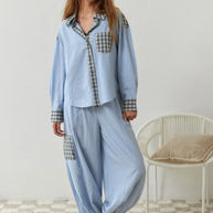 Eine Frau trägt ein 2-teiliges blaues, lässiges Pyjama-Set mit Karomuster