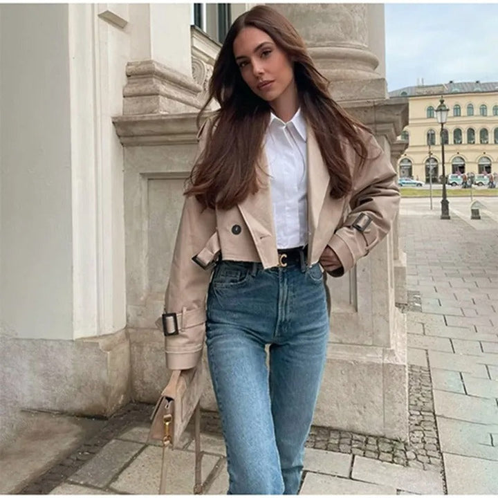Eine Frau trägt eine offene Kurzjacke mit weißem Innenoberteil und Jeanshose