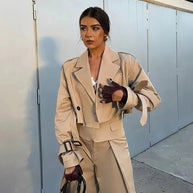 Ein Model in einer kurzen Jacke und Khakihosen, während es eine schwarze Tasche hält