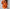 Frau in orangefarbener Bluse hält ihren Kragen vor eine weiße Wand