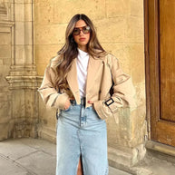 Ein Model trägt eine offene Kurzjacke mit weißem Innenoberteil und langem Jeansrock mit Schlitz