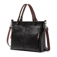Schwarze Ledertasche mit braunem Riemen auf weißem Hintergrund