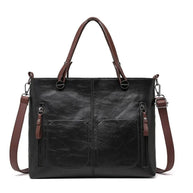 Schwarze Ledertasche mit braunem Riemen auf weißem Hintergrund