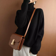 Ein modell in einem lose schwarz rollkragenpullover mit einer braunen umhängetasche
