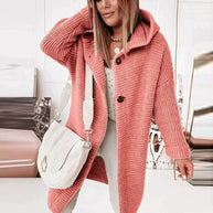 Eine Person trägt eine lange, warme rote Strickjacke mit Kapuze und zwei schwarzen Knöpfen